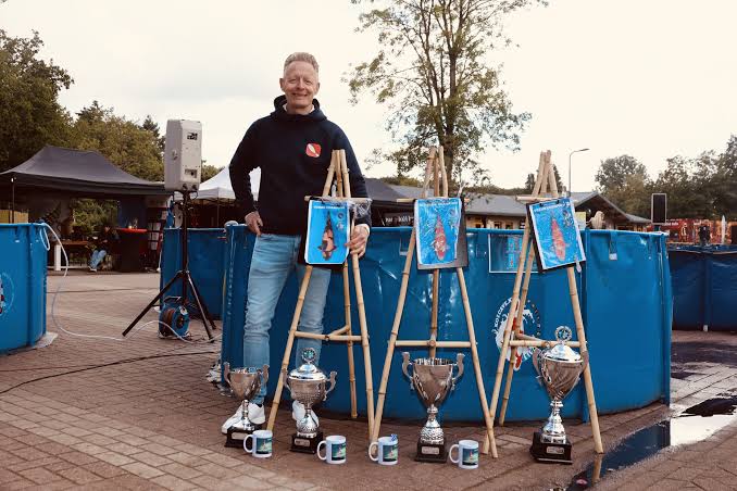 Geert Schrijvers met zijn bekers en showfoto's naast de showvats